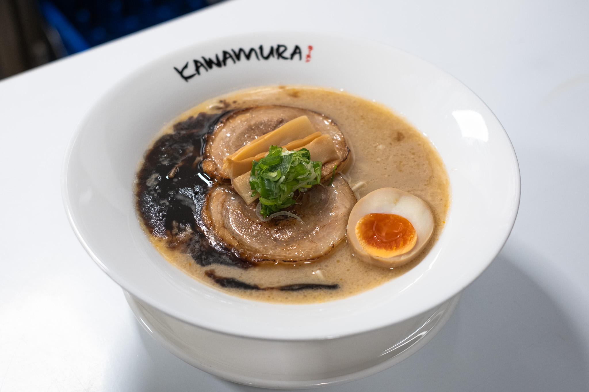 Black garlic oil tonkotsu ramen with chashu pork, bamboo shoots, and scallions at Kawamura Ramen Budapest